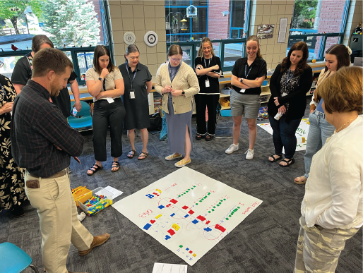 A large group of teachers gathered in a classroom learning an interactive math game for students.