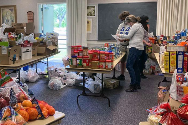 Several volunteers organize food and other supplies at a community donation cetner in a local church.