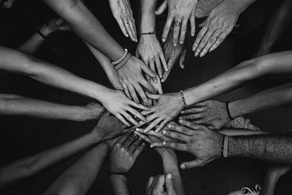 A circle of people putting their hands together.