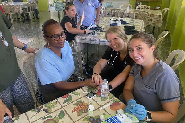 Shalese Evertsen and Alex Bushman at a table with a patient in a health clinic