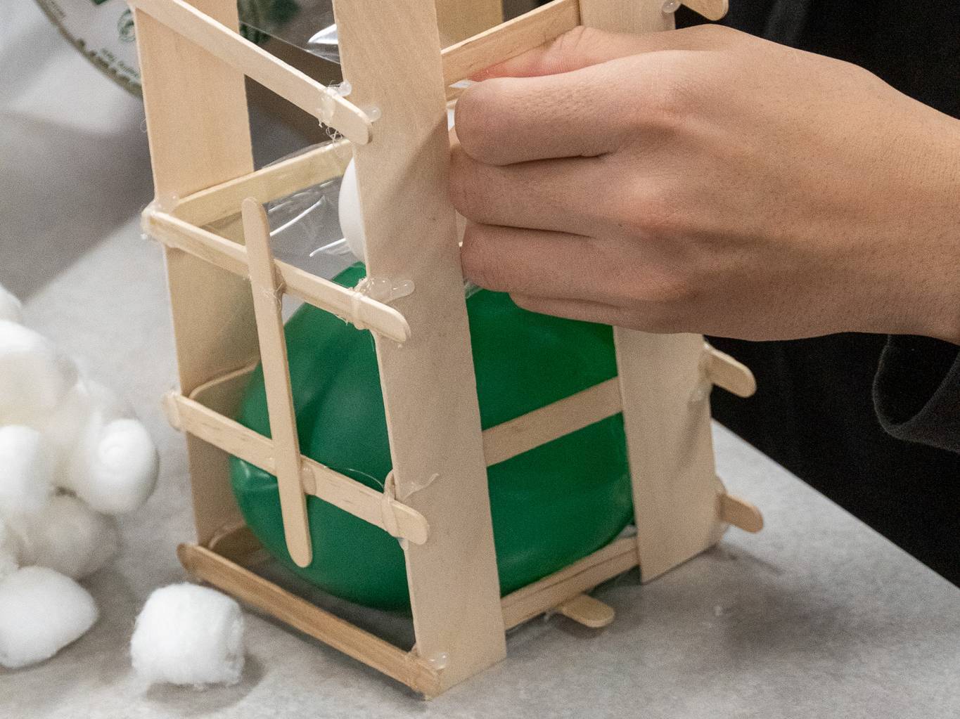 A picture of a student constructing a cage to protect an egg